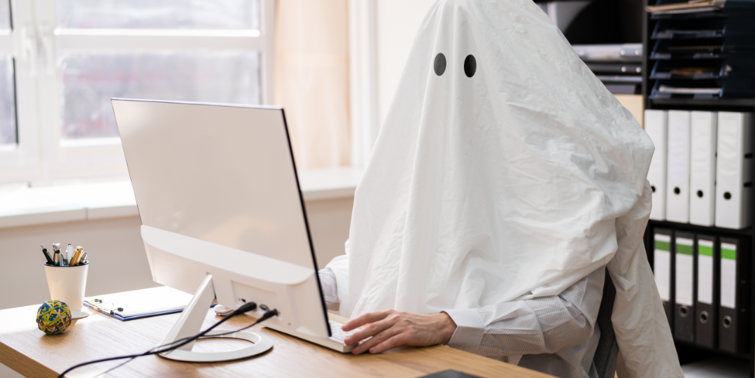 Person dressed as a ghost sitting at a desk using a computer, symbolizing what to do when your web designer ghosts you.